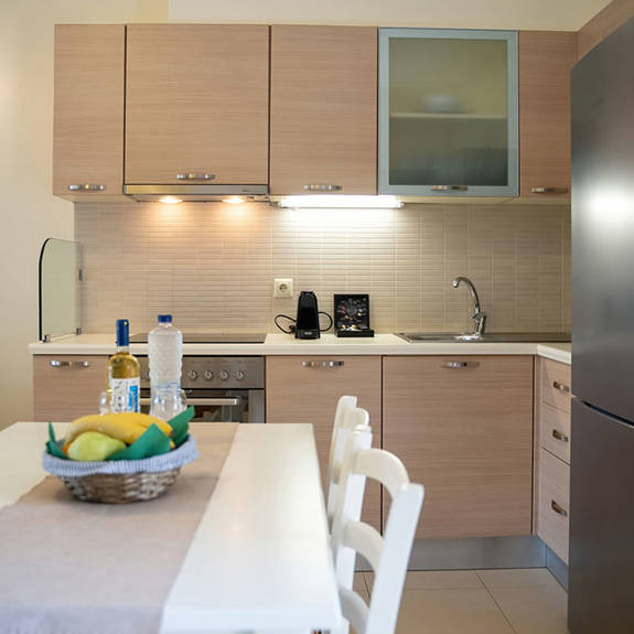kitchen table with fruits, wine and bottle of water, and counter with espresso machine in a two bedrooms apartment in plakias, rethymno, crete