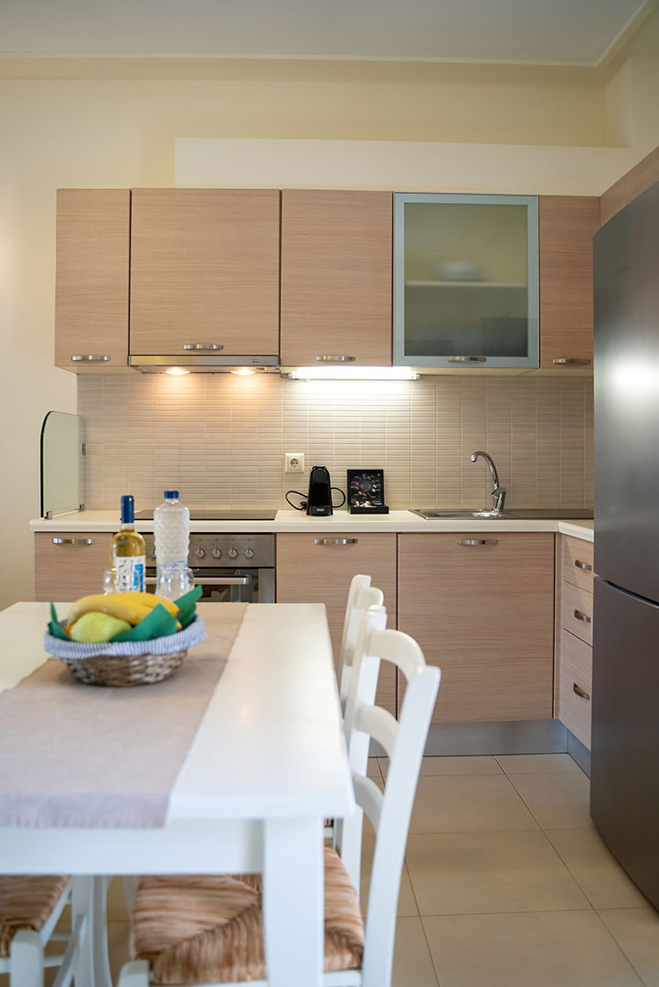 kitchen table with fruits, wine and bottle of water, and counter with espresso machine in a two bedrooms apartment in plakias, rethymno, crete