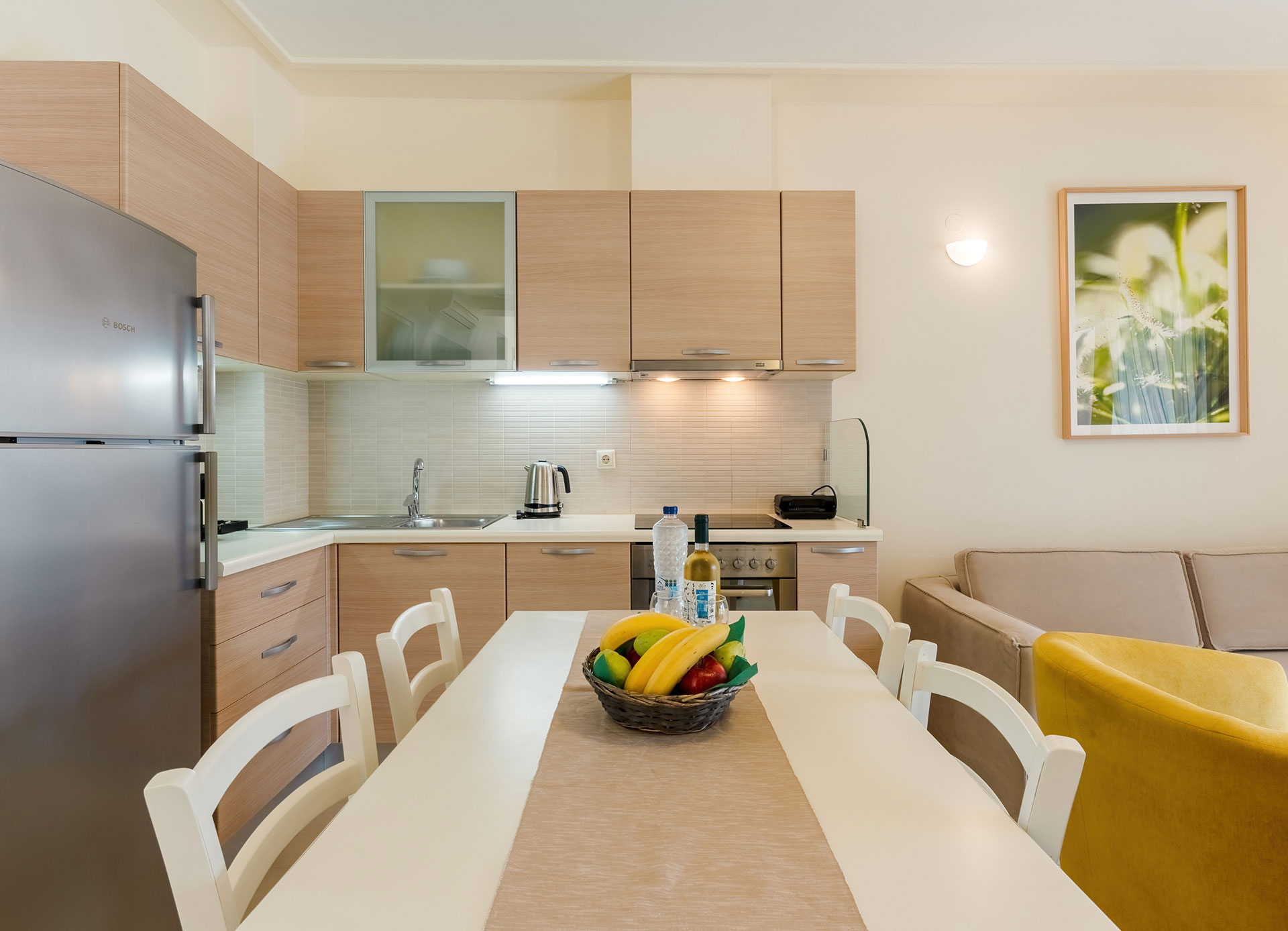 kitchen table with fruits, wine and bottle of water, and counter with kettle in a two bedrooms apartment in plakias, rethymno, crete