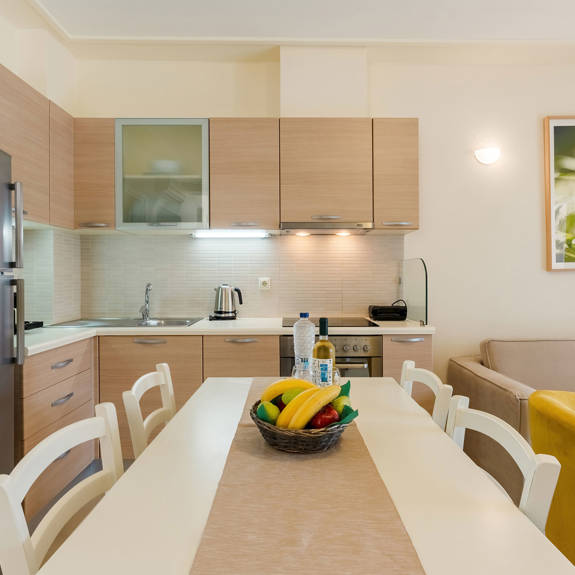 kitchen table with fruits, wine and bottle of water, and counter with kettle in a two bedrooms apartment in plakias, rethymno, crete