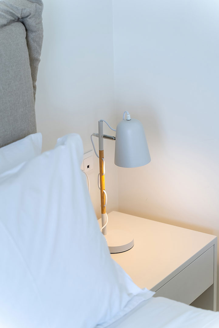 white bed sheets and reading lamp in a two bedrooms maisonette in plakias, rethymno, crete