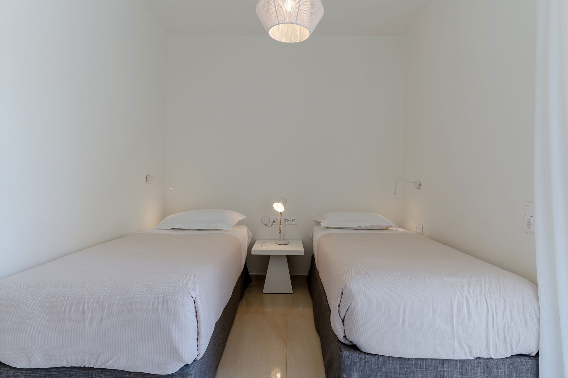 two single beds and bedside table with reading lamp in a two bedrooms maisonette in plakias, rethymno, crete