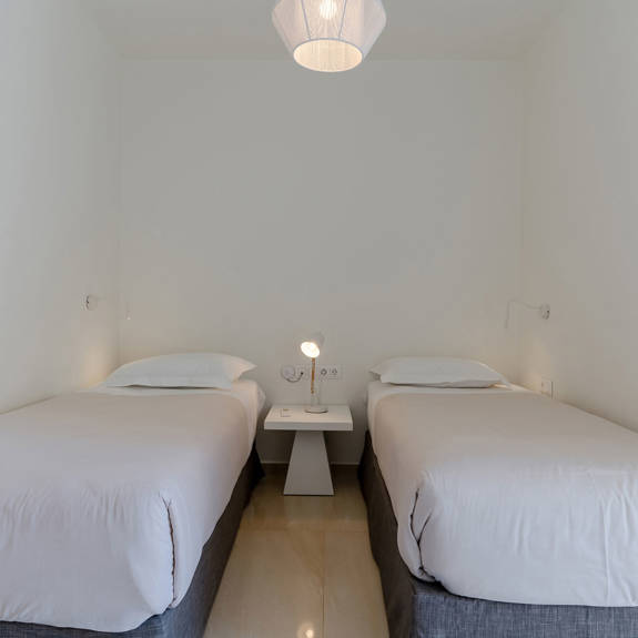 two single beds and bedside table with reading lamp in a two bedrooms maisonette in plakias, rethymno, crete
