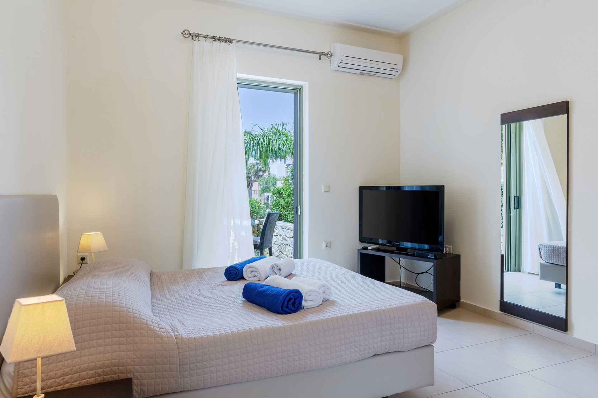 bedroom with tv and mirror in a studio in plakias, rethymno, crete